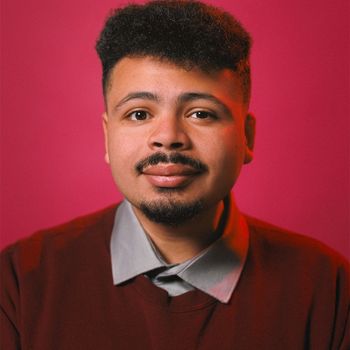A headshot of Andre Fenton with a dark pink background. 
