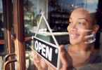 Photo of person turning over business window sign to say "open"