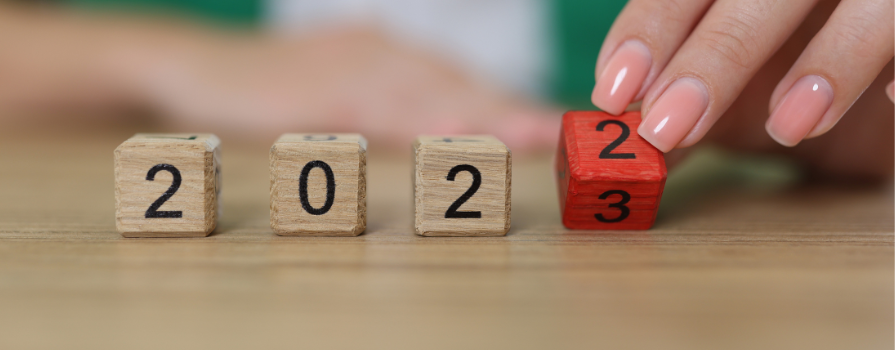 Closeup of a hand flipping wooden dice, changing from 2022 to 2023.