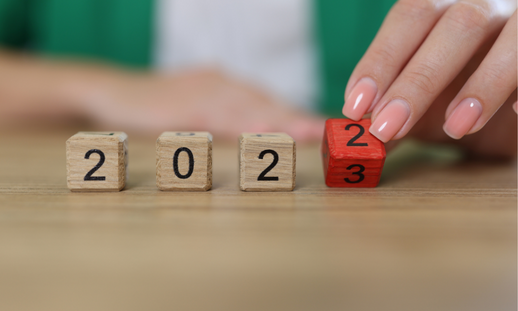 Closeup of a hand flipping wooden dice, changing from 2022 to 2023.