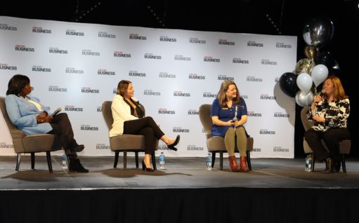 A panel of four women sitting on stage, engaging in conversation.