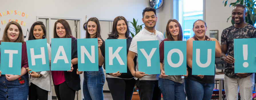 Photo of NSCC students holding blue signs with white text spelling, "Thank you!"