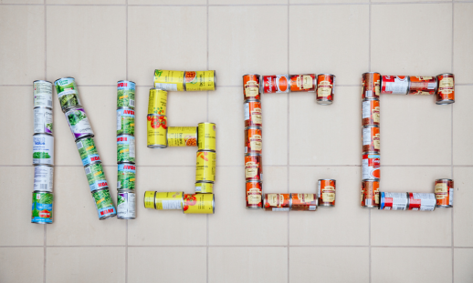 Photo of donated canned food spelling "NSCC".