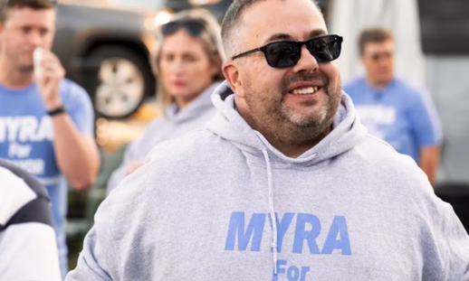 Jamie Myra in the street with people in the background wearing branded clothes in support of his campaign.