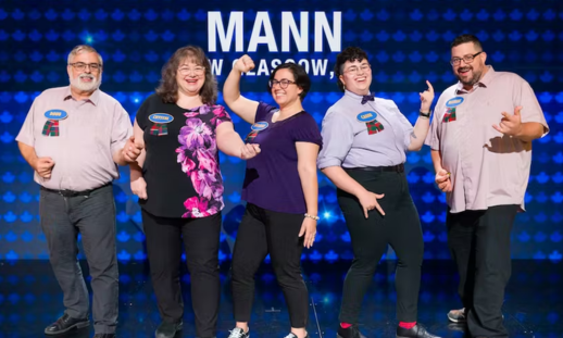 The Mann family (five people) wearing strips of the New Glasgow tartan on their name tags with the Family Feud blue light background and their name.
