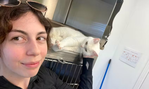 A selfie of Rolanda Nason with a white cat at the SPCA where she volunteers.