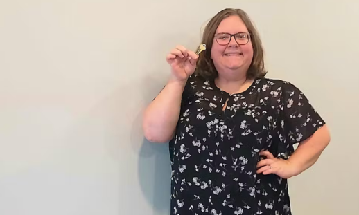 Stephanie Grant in the new brick-and-mortar of her business, holding her store key and smiling.