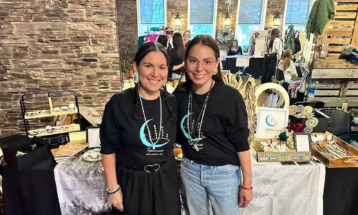 Sisters Rebecca and Theresa Scirocco, co-owners of Tepknuset Art and Wellness, standing in front of their vendor table at the Cape Breton Centre for Craft & Design for the Mi'kmaw Christmas Market. 