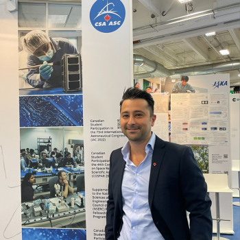 Arad standing in front of a pull-up banner for the Canadian Space Agency.