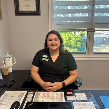 A female nurse in uniform sitting at her office desk.