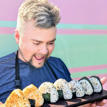 Liam Crane holding a tray of seven sushi rolls.