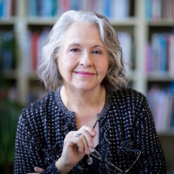 A headshot of Lesley Crewe with an out of focus bookshelf in the background.