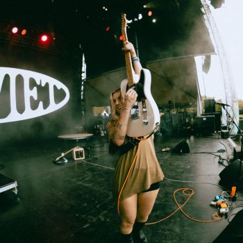 A woman playing electric guitar on stage during a rock concert.