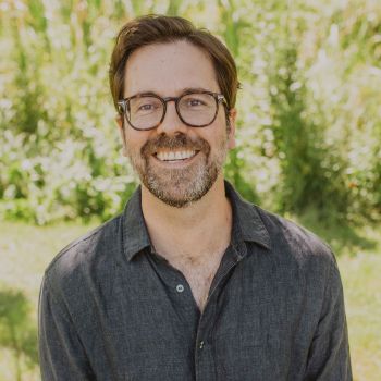 A headshot of Tom Ryan outside with trees in the background.