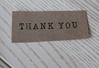 Photo of brown piece of paper that says "Thank you" in black text.