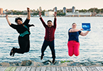 Photo of NSCC graduates happily jumping in the air in at a waterfront.