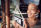 Photo of woman turning business sign that says open