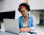 Photo of woman smiling while looking at a laptop.