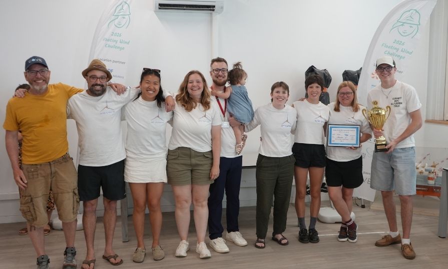 A photo of the Scotian Gales team (eight people) with their supervisor and a team member holding his daughter. They are standing next to each other, with a teammate holding their trophy.