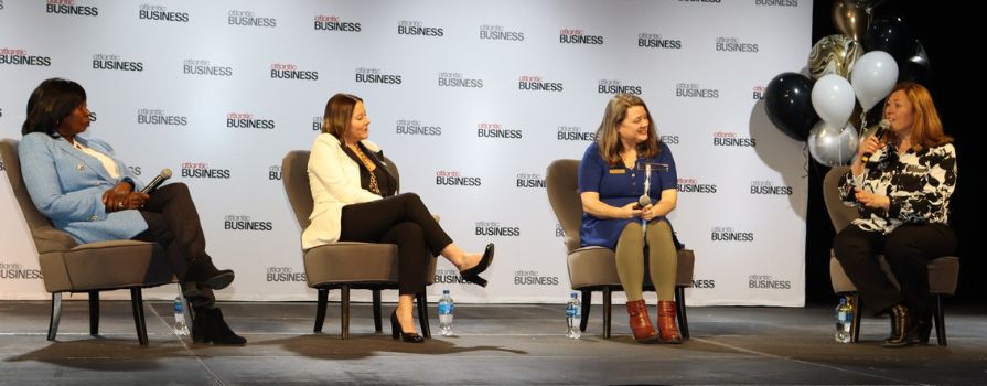 A panel of four women sitting on stage, engaging in conversation.