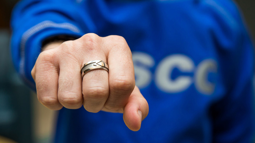A woman wearing an NSCC with her arm outstretched showing the Alumni Ring. 