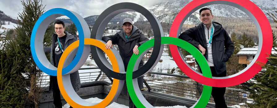 From left to right: NSCC alumni Ben Medleson, Neil Gordon and Alex Cook at the 2026 Winter Olympics sign.