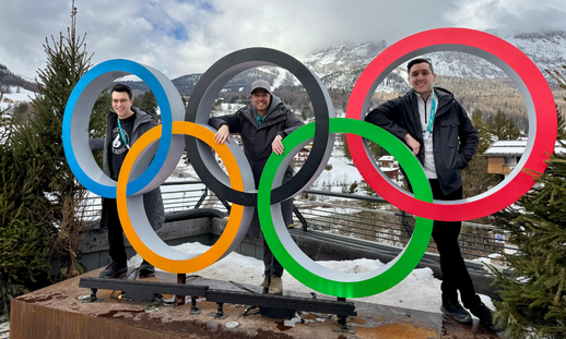 From left to right: NSCC alumni Ben Medleson, Neil Gordon and Alex Cook at the 2026 Winter Olympics sign.