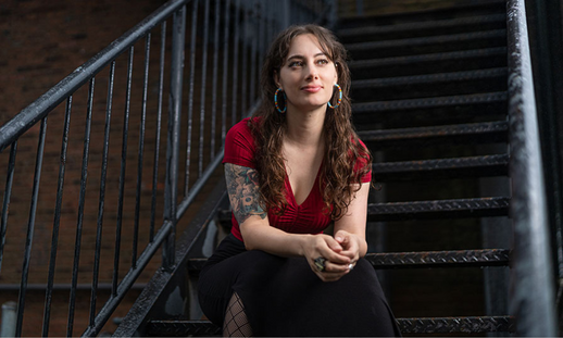 Stephanie Joline sitting on a mental staircase outside of a brick building.