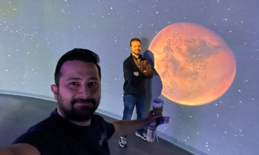 NSCC grads Arad and Luc from GALAXIA Mission Systems in front of a moon photo.