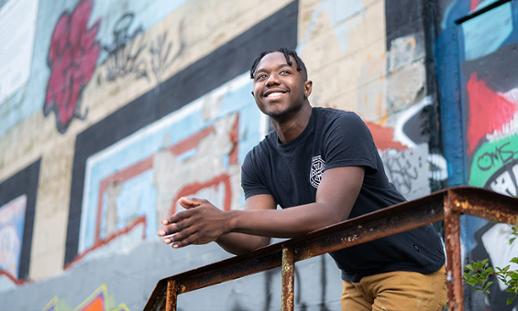 Keandre Johnson leaning on a railing of a building covered in graffiti.