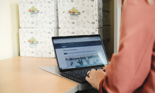 A woman looking at the NSCC Alumni website on a laptop.