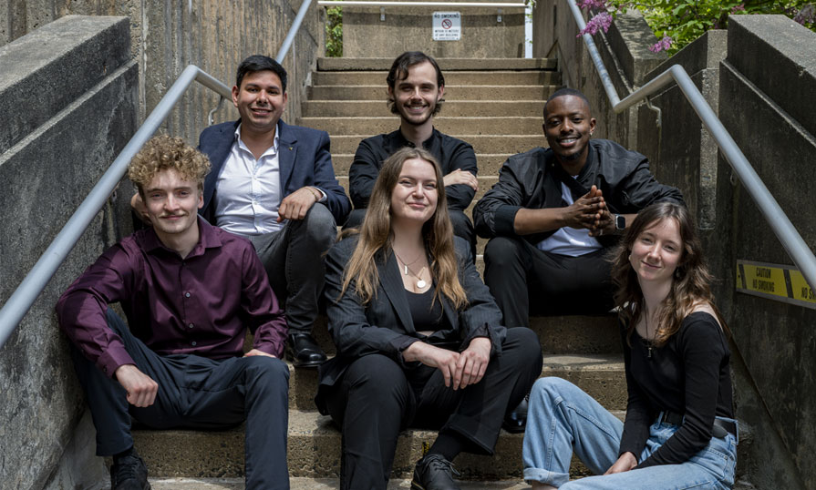 Six Music Business students sit on a set of stairs outside.