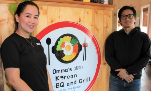 Mary Grace Gomez, left, and Joshua De Leon, right, stand in the front entrance of their restaurant, Omma's Korean Bar BQ and Grill.