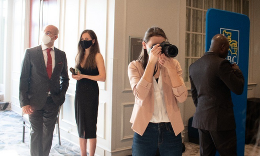 Hannah Jackson mid-taking a photo at a business event with a few guests in the background. 