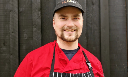 Headshot of Liam Crane wearing chef uniform and apron.
