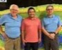 Three researchers smiling in front of a large geomatics map on a wall.