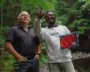 A business owner and researcher looking at data on a tablet in a forest.