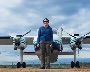 A researcher standing in front of a small airplane used for aerial mapping.