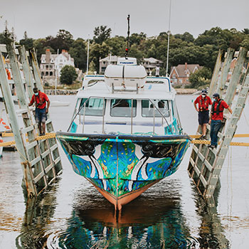 A boat being launched with beautiful Mi’kmaw artwork covering the hull of the boat.