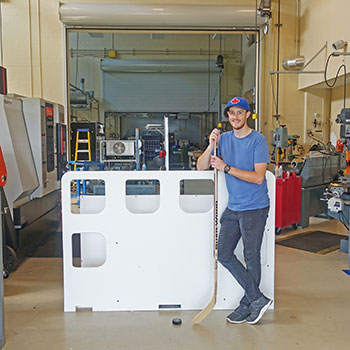 Research assistant, Tommy MacNaughton, in the Design & Innovation Centre with the hockey training device.