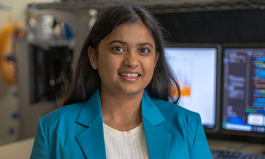 Woman sitting in front of data on computers smiling. 