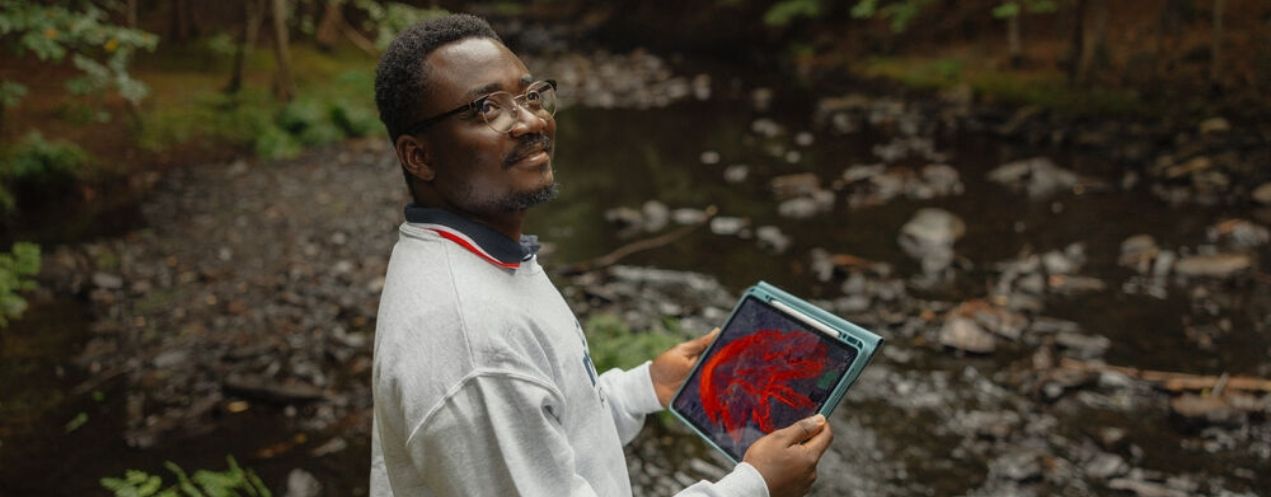 Research assistant reviewing data on a tablet while conducting fieldwork in a forest.
