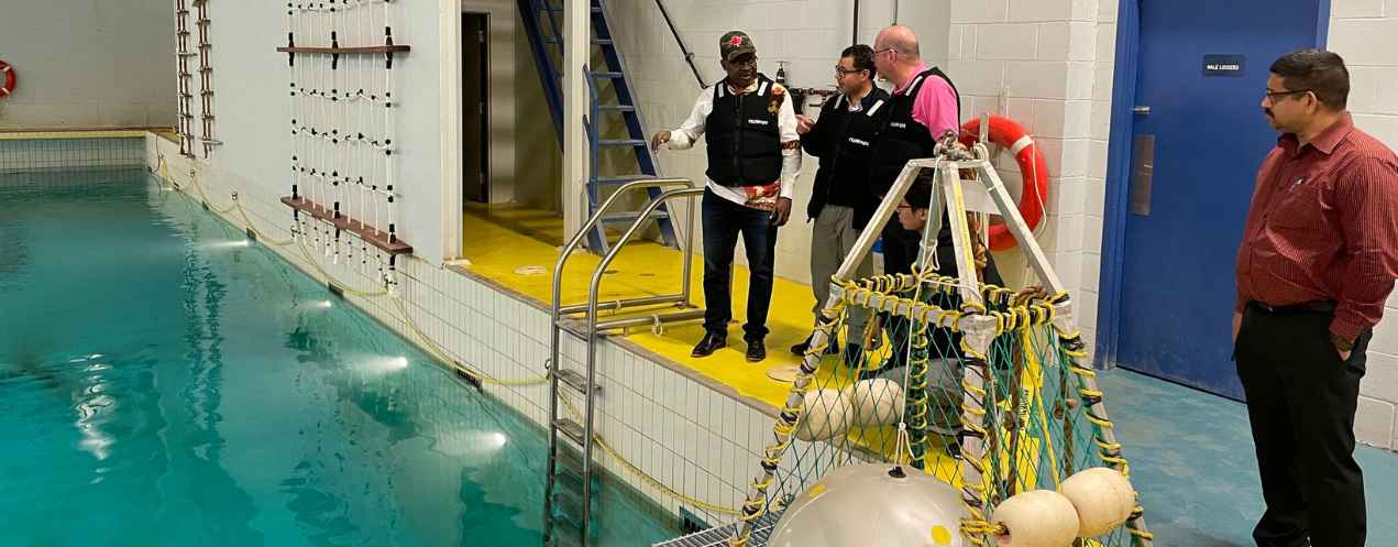 A couple of people in discussion beside an industrial pool, with a large hydro turbine device positioned at the edge.