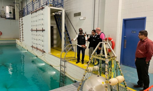 A couple of people in discussion beside an industrial pool, with a large hydro turbine device positioned at the edge.