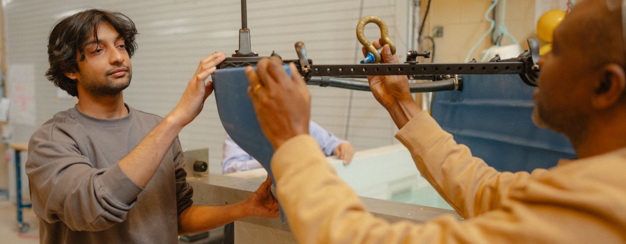 Two individuals placing a device into a water tank in a laboratory environment.