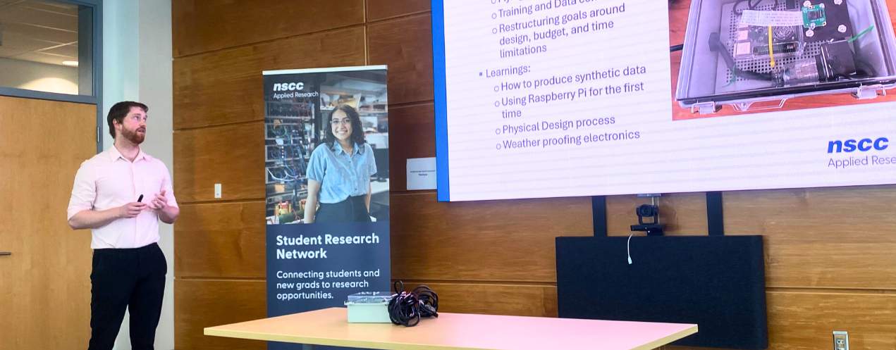 A young man presenting with a prototype displayed on the table beside him.