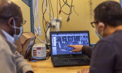 Two men in a research lab looking at simulation software on a computer. 