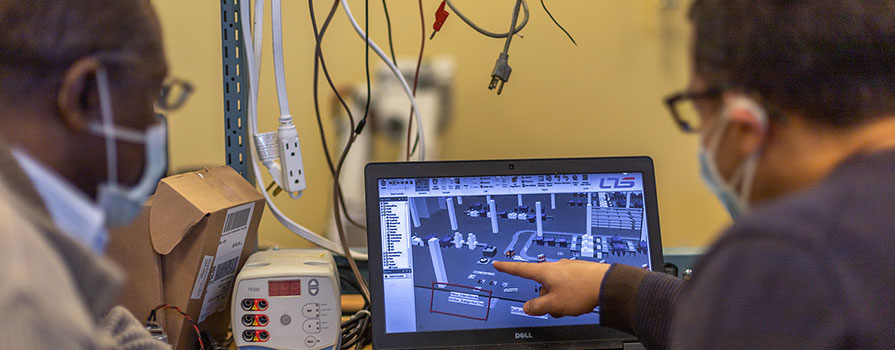 Two men in a research lab looking at simulation software on a computer.
