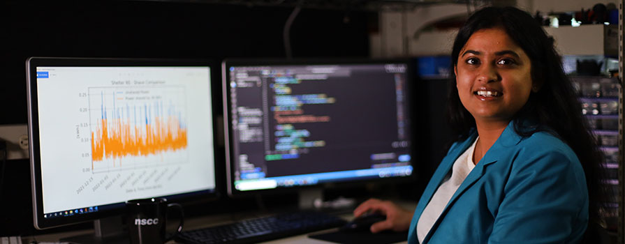 Woman researcher looking at two monitors showing complex data. 