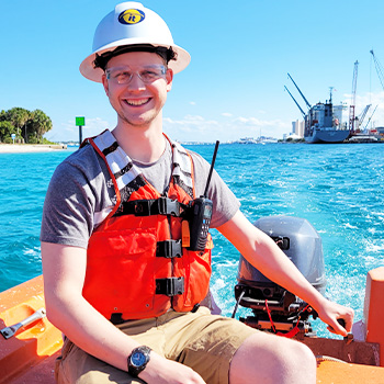 Captain Arran sitting on the deck of a boat while smiling